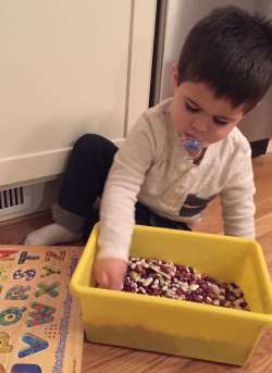 Young Child Playing with a Bucket of Dried Beans