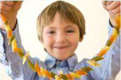 Kid holding macaroni necklace craft